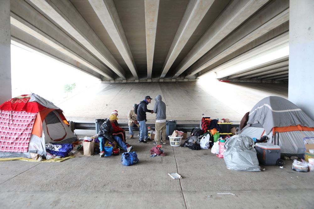 Homeless men in 2019 are seen outside their tents under a bridge in Austin, Texas.